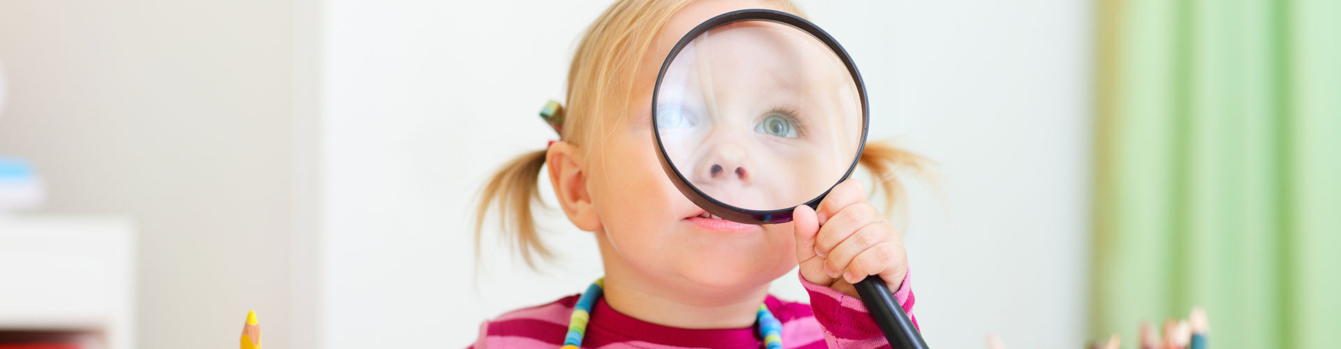 Toddler girl looking through magnifying glass