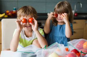 children playing with tomatoes over their eyes