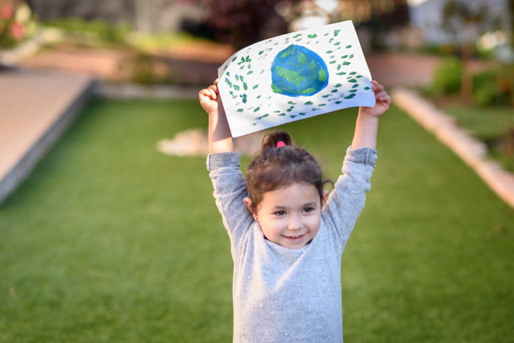Portrait of the cute little girl holding the drawing earth globe. Child drawnig a picture of earth.